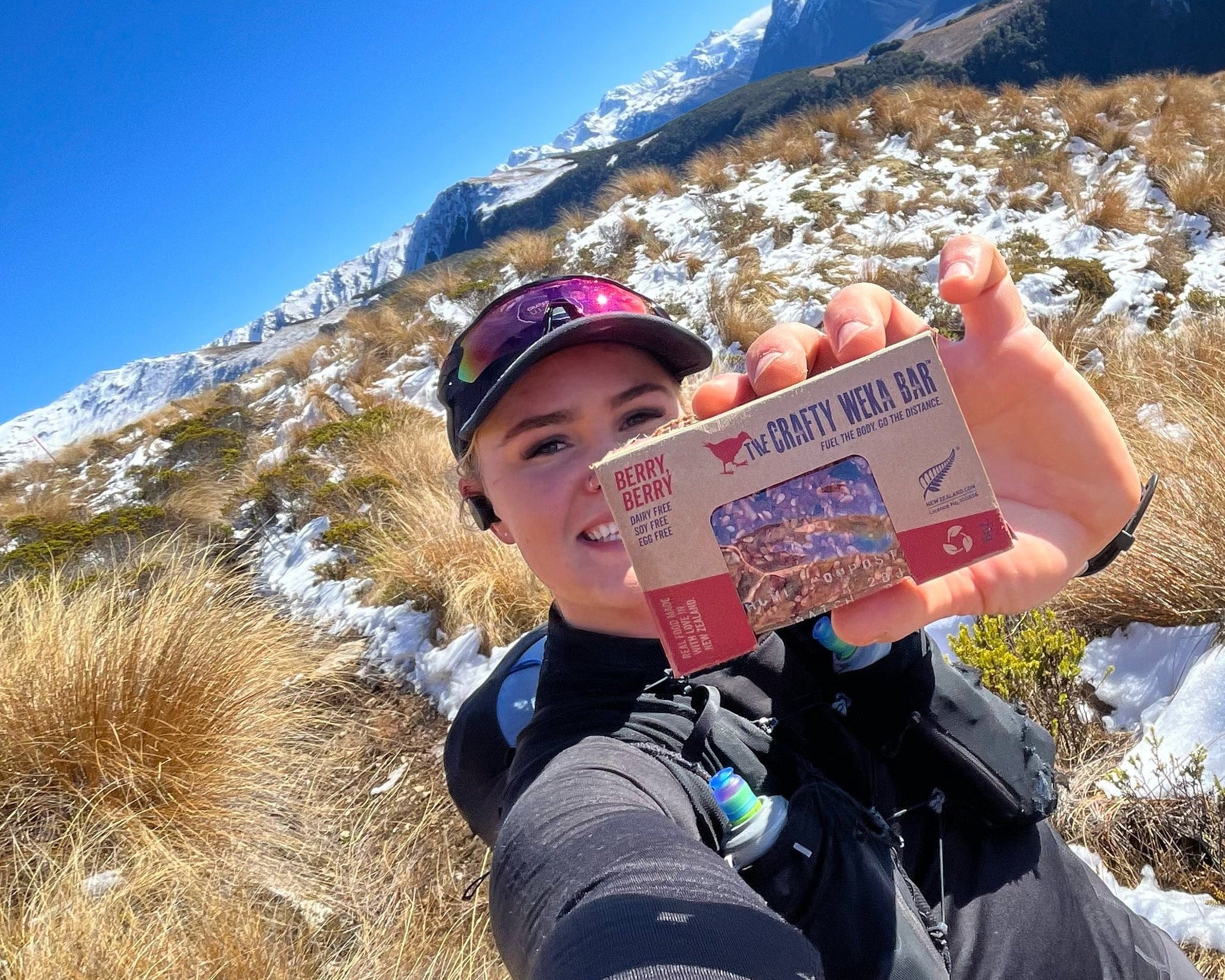 Person holding a crafty weka bar in front of a mountainous landscape